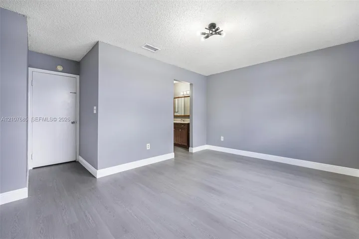 Room featuring wood-finish flooring, neutral gray wall paint, and multi-light flush mount ceiling fixture