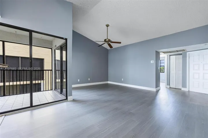 Vaulted ceilings, wood-finish flooring, ceiling fan, and sliding glass doors with direct access to a private balcony