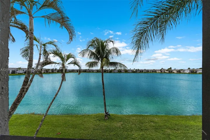 Waterfront property featuring a manicured grass lawn and mature palm trees