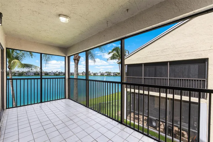 Screened-in balcony featuring tile flooring, metal railings, and stucco exterior walls