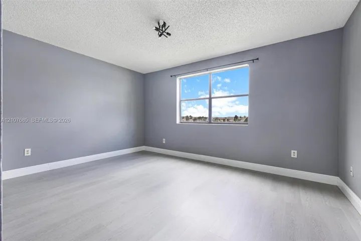 Room featuring wood-finish flooring, neutral-toned walls, and a multi-pane window with a curtain rod