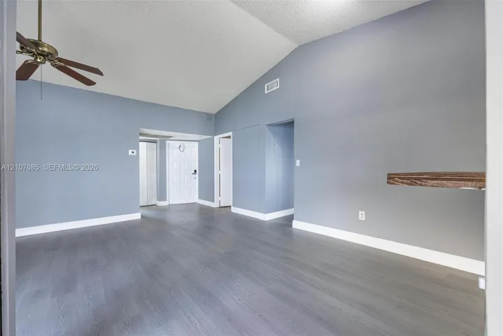 Vaulted ceilings, wood-finish flooring, and a ceiling fan with integrated lighting