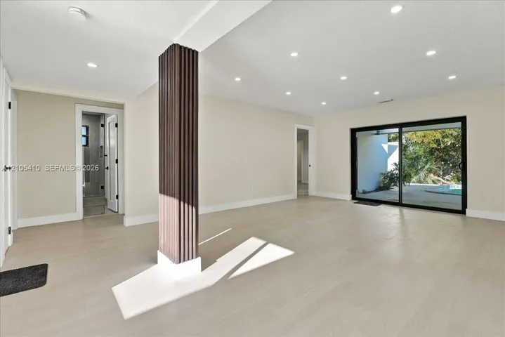 Open floor plan featuring wood-finish flooring, recessed lighting, a structural column with vertical architectural detailing, and large sliding glass doors