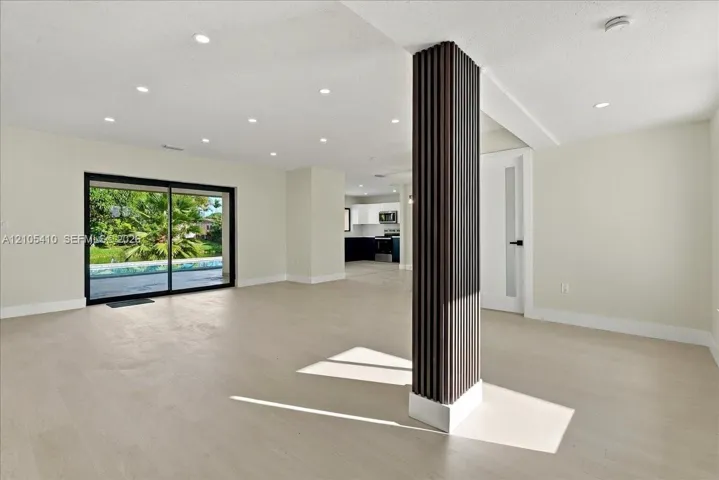 Open interior featuring wood-finish flooring, recessed lighting, a decorative fluted support column, and large sliding glass doors