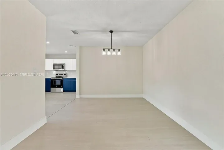 Open-concept interior featuring wood-finish flooring, a contemporary multi-light chandelier, and recessed lighting