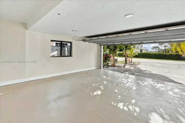 Garage interior featuring neutral wall paint, recessed lighting, a single-pane window, and painted concrete flooring