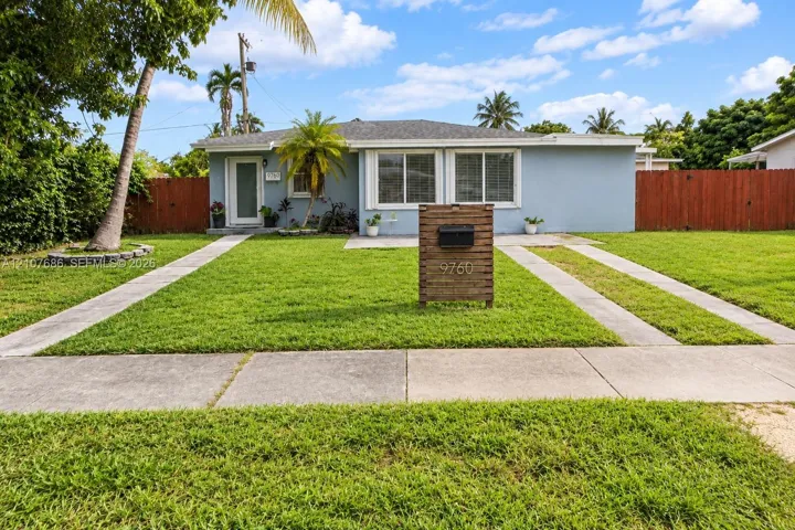 Single-story exterior featuring light-toned masonry, a horizontal wood-slat mailbox pedestal, dual-pane windows, and a paved concrete driveway