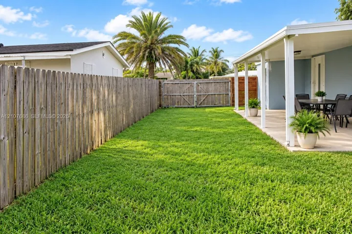 Fenced backyard featuring a manicured lawn, a covered concrete patio, and vertical wood privacy fencing