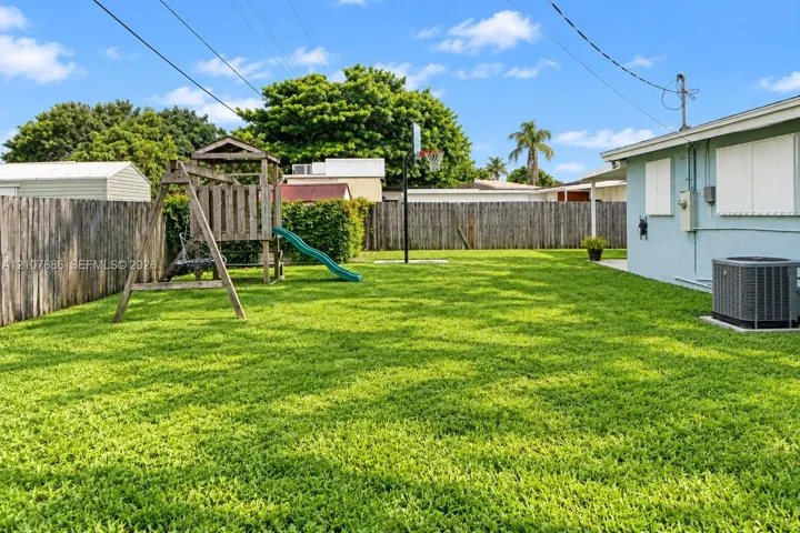 Expansive backyard featuring a fenced perimeter, manicured lawn, and exterior wall-mounted shutter panels