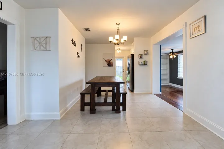 Dining area featuring light-toned tile flooring, a multi-arm chandelier, and a brushed stainless steel refrigerator