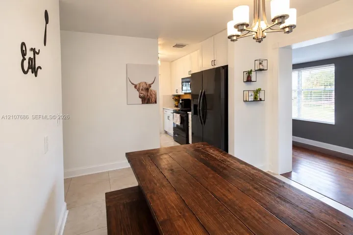 Kitchen featuring white cabinetry, black appliances, tile flooring, and a multi-arm ceiling-mounted light fixture