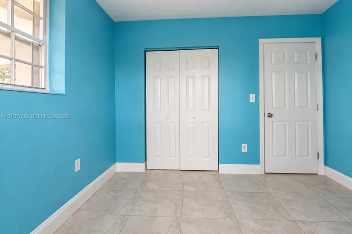 Interior room featuring tile flooring, a multi-pane window, and a white six-panel closet door