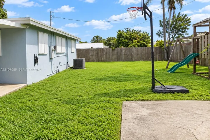 Expansive backyard featuring a level lawn, concrete patio, and full-height wood fencing