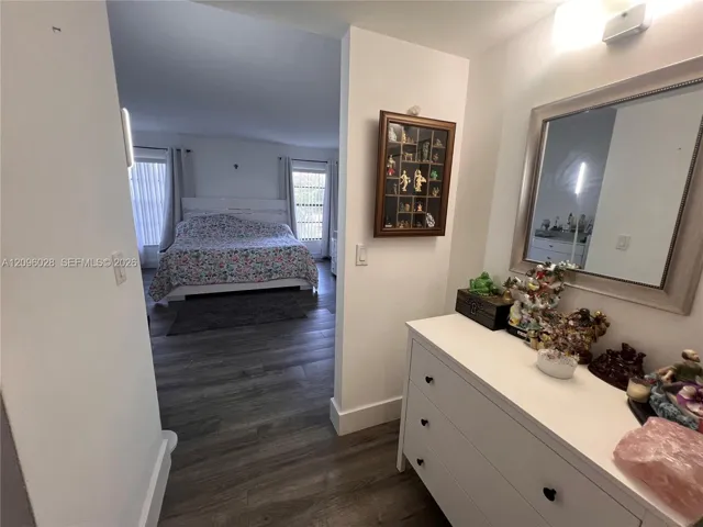 Wood-finish flooring throughout, wall-mounted rectangular mirror with a metallic frame, and overhead lighting fixtures