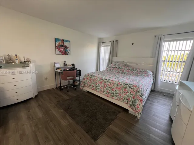Wood-finish flooring, neutral wall tones, and large windows with vertical blinds
