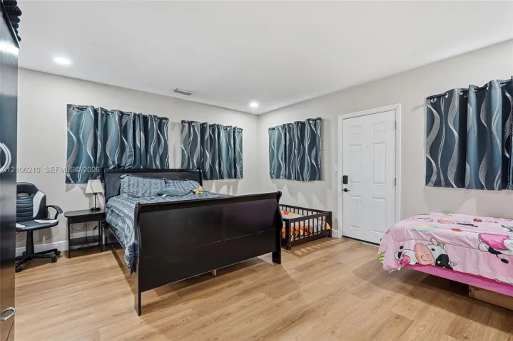 Neutral-toned interior featuring wood-finish flooring, recessed lighting, and a solid-panel door with electronic keypad entry