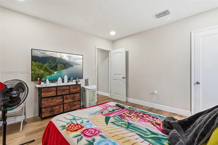Neutral interior room featuring wood-finish flooring, recessed lighting, and white arched-panel doors