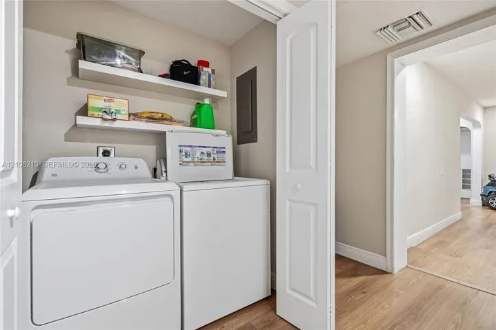 Laundry area featuring two white built-in shelves and a bi-fold door