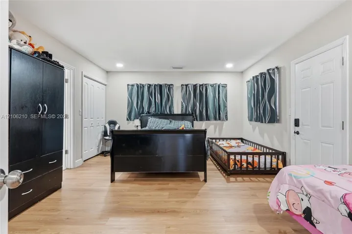 Spacious room featuring wood-finish flooring, recessed lighting, and multi-panel interior doors