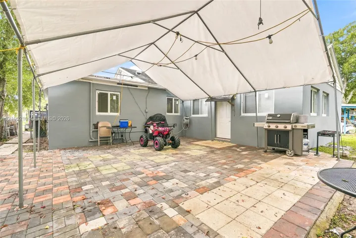 Exterior patio featuring multi-tonal paver hardscaping and a metal-frame canopy structure