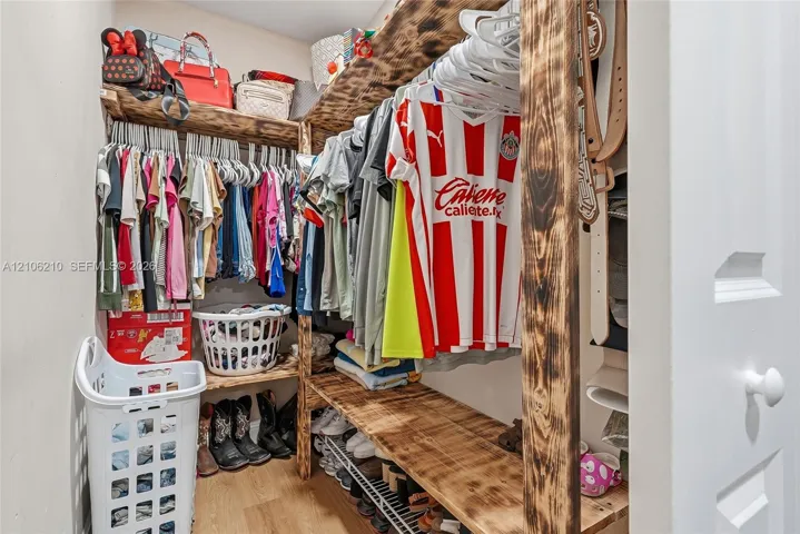 Custom walk-in closet featuring multi-level natural wood shelving and integrated rod storage