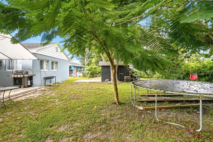 Exterior grounds featuring a concrete patio, mature landscaping, and a detached structure