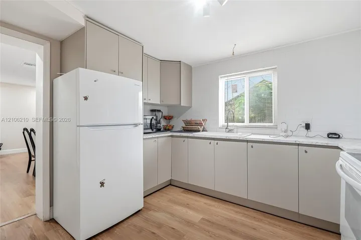 Kitchen featuring flat-panel cabinetry, stone-finish countertops, subway tile backsplash, stainless steel sink with gooseneck faucet, and wood-finish​​‌​​​​‌​​‌‌​‌‌​​​‌‌​‌​‌​‌​​​‌​​ flooring