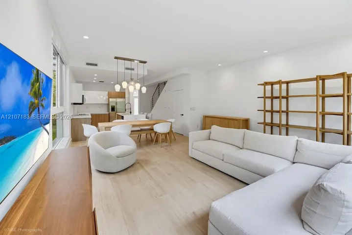 Open-concept living space featuring wood-finish flooring, recessed lighting, and a modern kitchen with flat-panel cabinetry and a multi-pendant light fixture