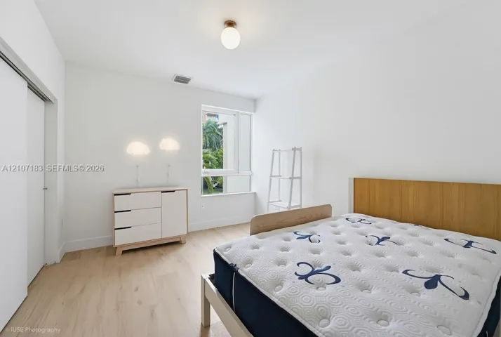 Bedroom featuring wood-finish flooring, a large window, sliding-door closet, and modern ceiling lighting