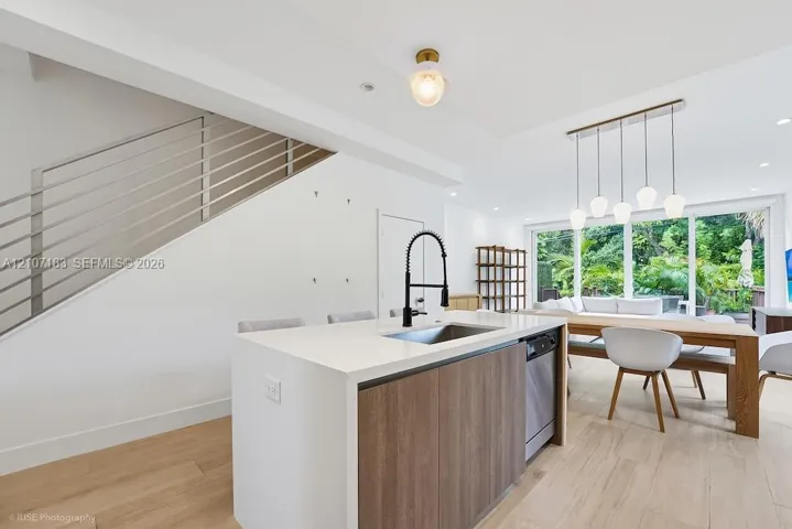 Kitchen island featuring a stone countertop, wood-finish cabinetry, and a gooseneck faucet