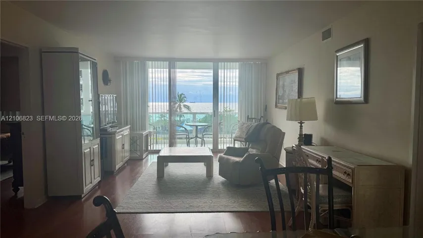 Living area featuring wood-finish flooring, floor-to-ceiling sliding glass doors, and direct access to an exterior balcony