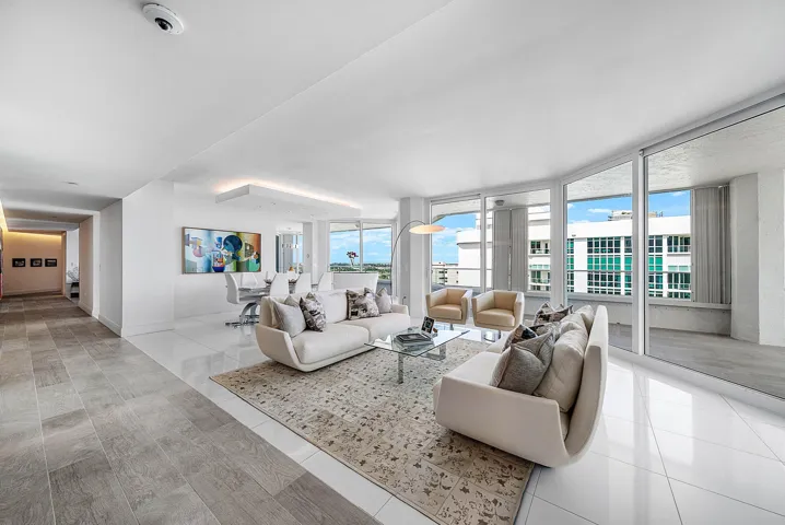 Open-concept interior featuring large-format tile flooring, floor-to-ceiling windows, and a recessed ceiling architectural detail with integrated lighting