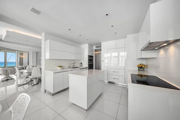 Modern kitchen featuring high-gloss cabinetry, stone countertops, integrated appliances, a central island, and large-format tile flooring
