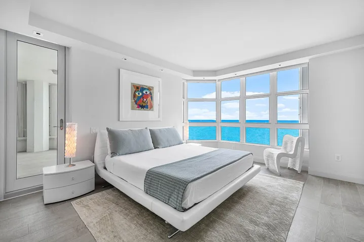 Bay window featuring ocean water, wood-finish flooring, and recessed ceiling lighting