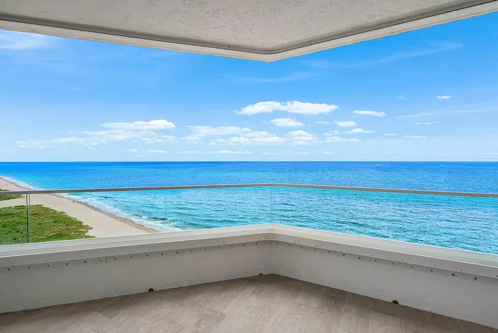 Covered balcony featuring wood-finish flooring and frameless glass railings