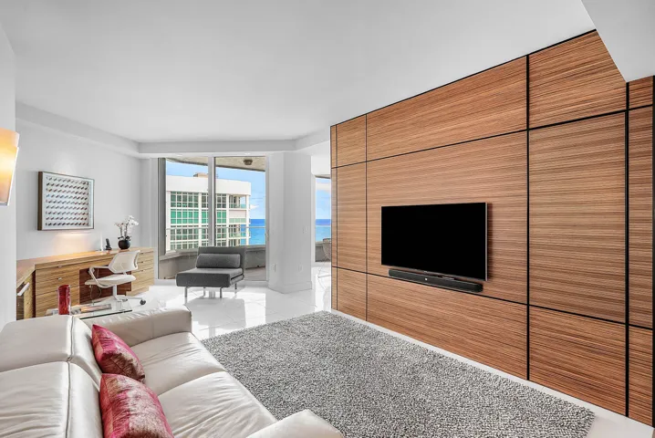 Floor-to-ceiling wood-panel accent wall, built-in desk cabinetry, floor-to-ceiling glass windows, and polished tile flooring