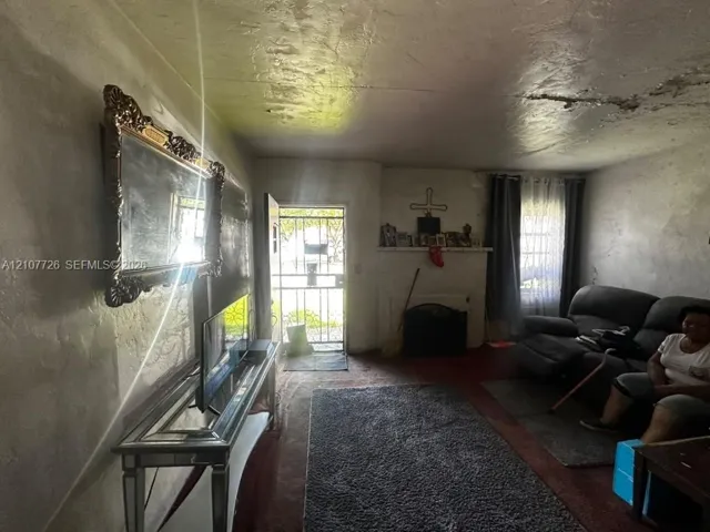 Interior room featuring a built-in mantel, wood-finish flooring, and a metal security storm​​‌​​​​‌​​‌‌​‌‌​​​‌‌​‌​‌​‌​​​‌​​ door