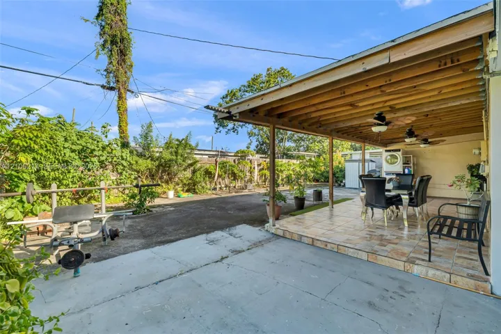 Covered patio featuring ceramic tile flooring, exposed wood beam ceiling, and dual ceiling fans