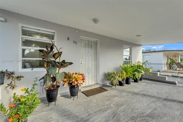 Covered entryway featuring large-format stone-style flooring, a metal security screen door, and horizontal-pane windows