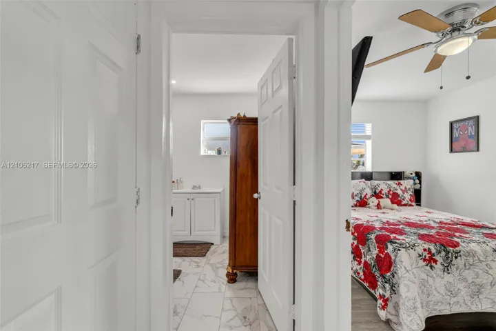Interior doorway featuring a white six-panel door, ceiling-mounted light fixture with fan blades, and tile flooring
