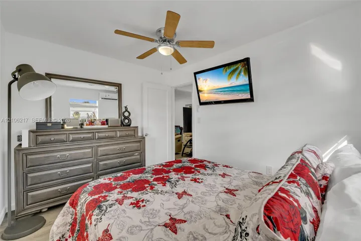 Room featuring a multi-blade ceiling fan with integrated lighting and a wall-mounted ductless mini-split unit