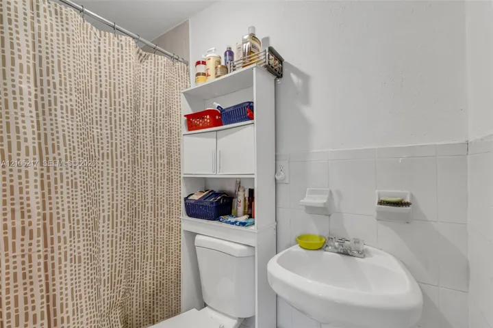Wall-mounted sink with chrome-finish faucet, built-in ceramic soap dish, and white tile wainscoting