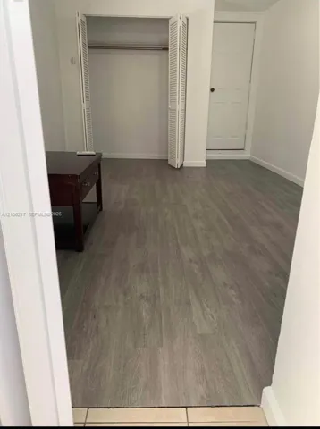 Neutral-toned wood-finish flooring, white walls, and a closet with bifold doors