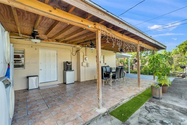 Covered patio featuring a wood-beam ceiling, tile flooring, and multiple ceiling fans