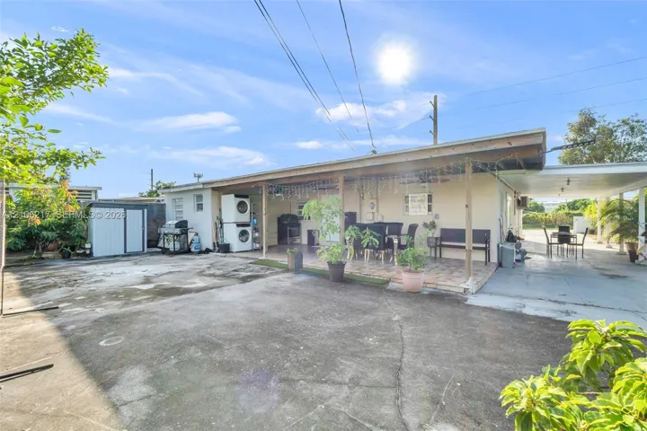 Concrete patio area with a covered porch, detached storage shed, and a secondary covered carport