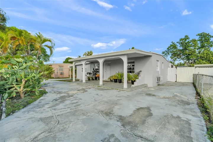 Single-story exterior featuring a covered front porch with arched support columns and concrete paved driveway