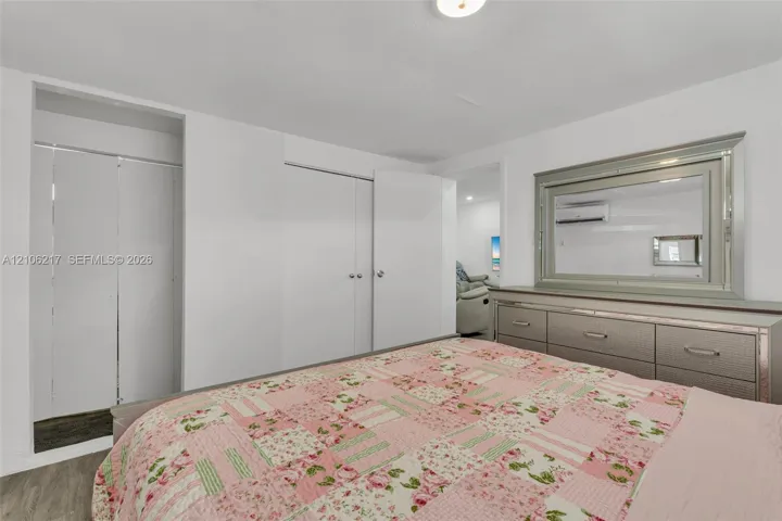 Interior space featuring neutral wall paint, white bi-fold closet doors, and wall-mounted air conditioning unit