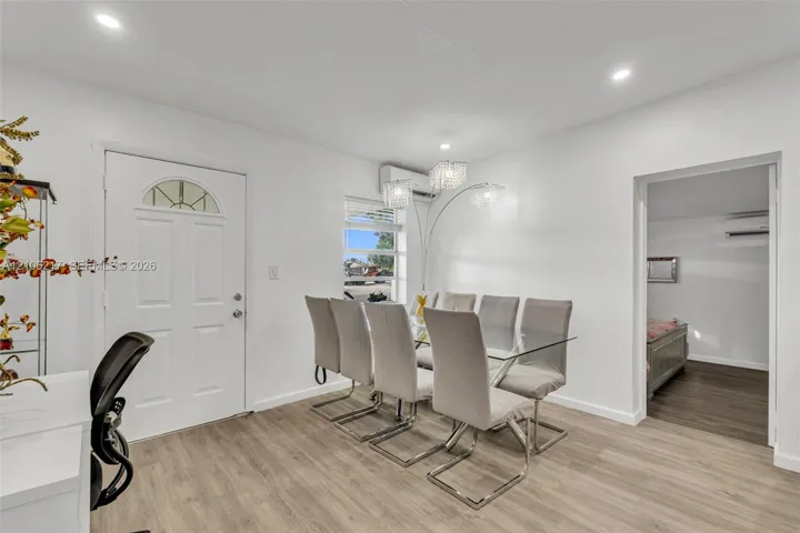 Interior space featuring light-toned wood-finish flooring, recessed lighting, multi-light chandeliers, and a wall-mounted ductless heating and cooling unit