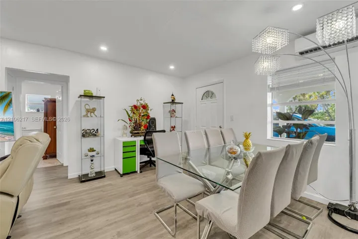 Open-concept interior featuring light wood-finish flooring, recessed lighting, and a wall-mounted climate control unit