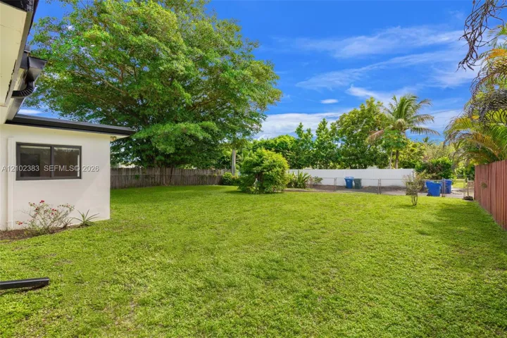 Expansive backyard featuring a manicured lawn, mature trees, white vinyl privacy fencing, and a side wood-panel​​‌​​​​‌​​‌‌​‌‌​​​‌‌​‌​‌​‌​​​‌​​ fence
